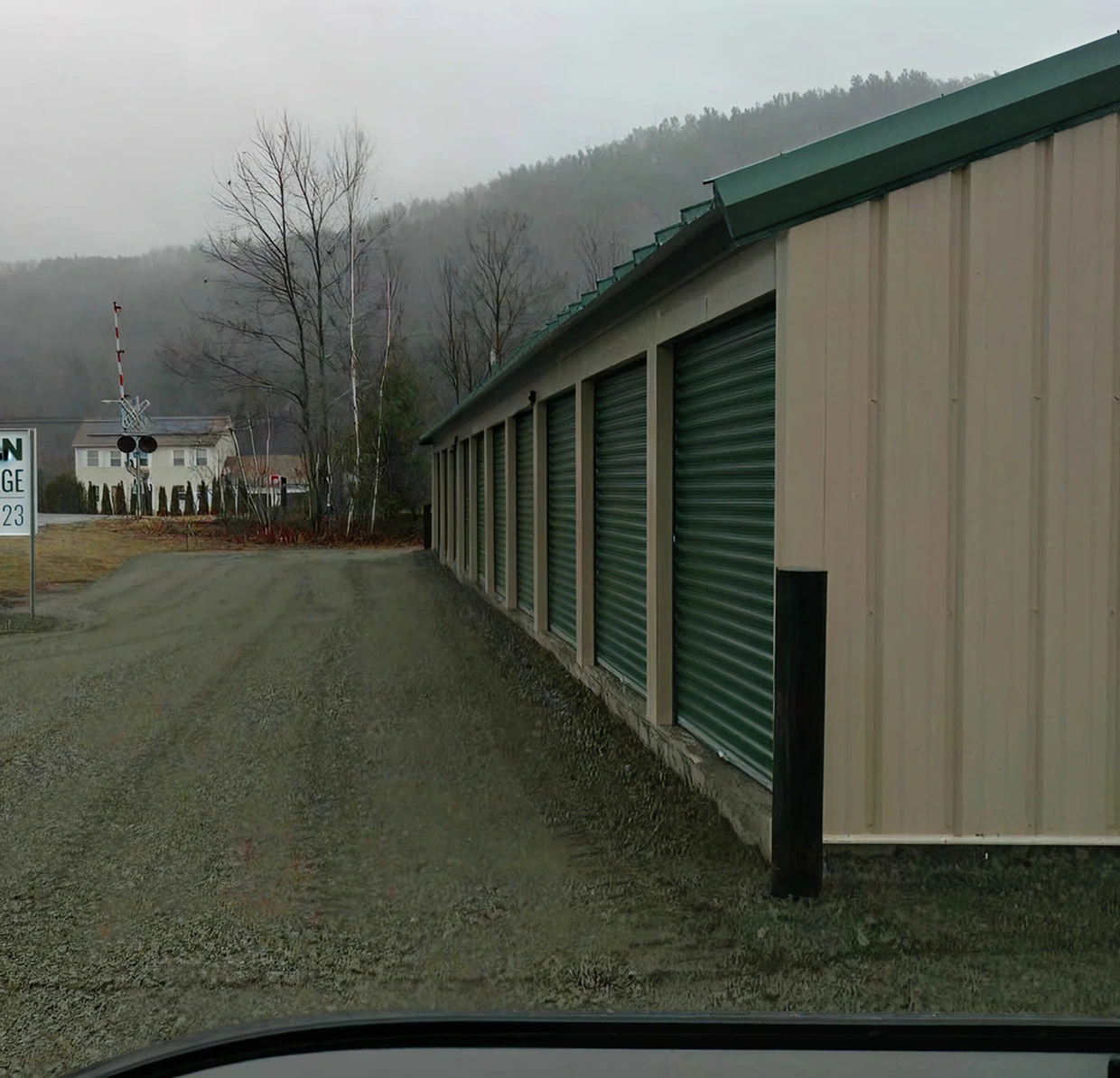 Storage units with green doors beside road.